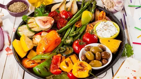 Raznobojno grillano povrće i voće posluženo na velikom crnom tanjuru.