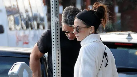 Sandra Bullock u bijelom puloveru s crnom trakom u kosi na parkiralištu.