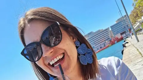 Zlata Mück Sušec sa sunčanim naočalama i plavim naušnicama nasmijana na suncu.