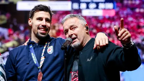 Ivan Martinović s medaljom oko vrata stoji pokraj pjevača na pozornici.