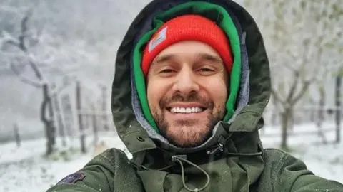 Nasmijani Luka Nižetić u zelenoj zimskoj jakni i crvenoj kapi na snijegu.