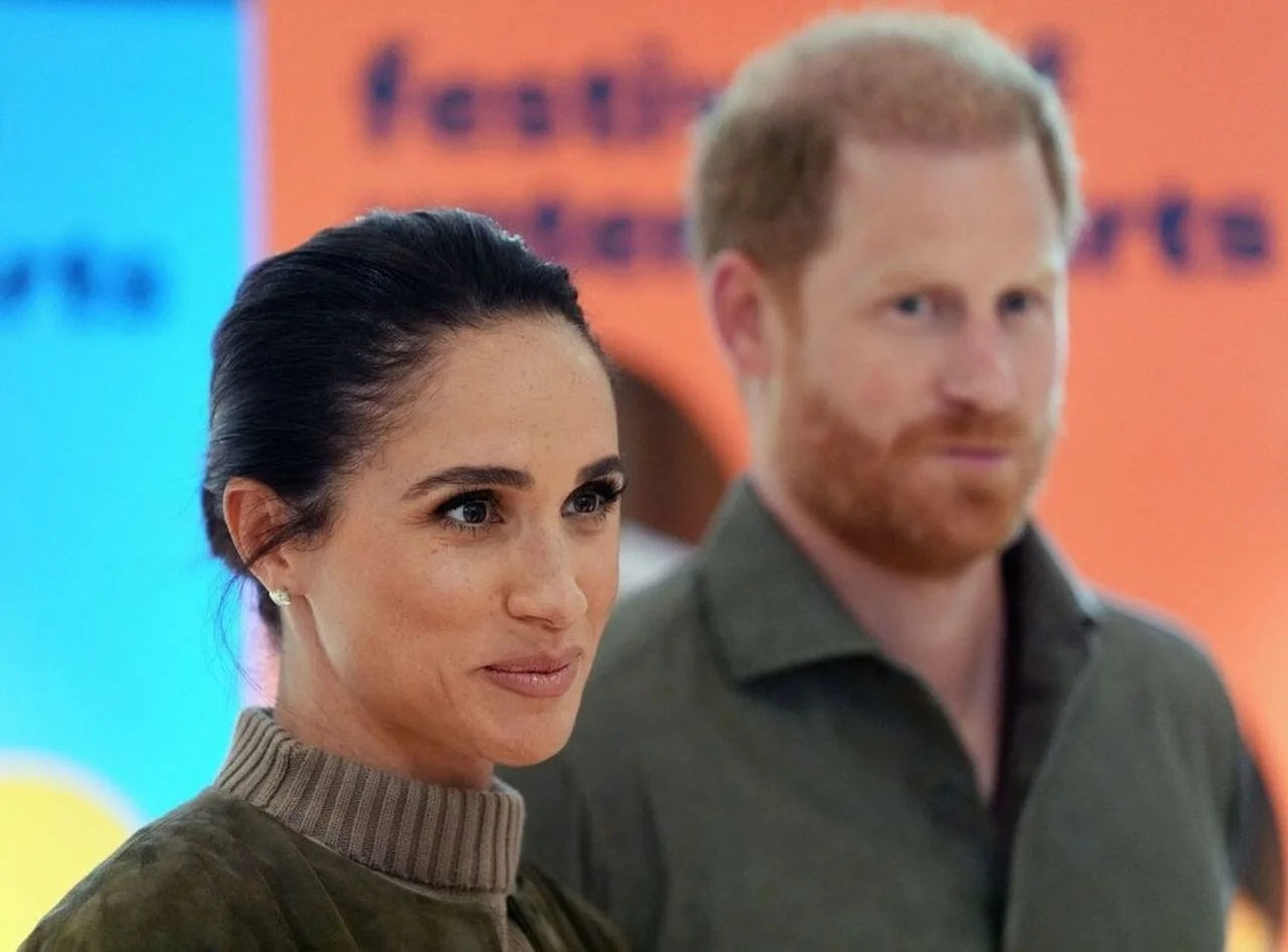 Princ Harry i Meghan Markle stoje zajedno ispred šarene pozadine