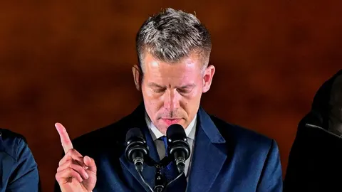 Péter Magyar govori za govornicom s mikrofonima i podignutim prstom.