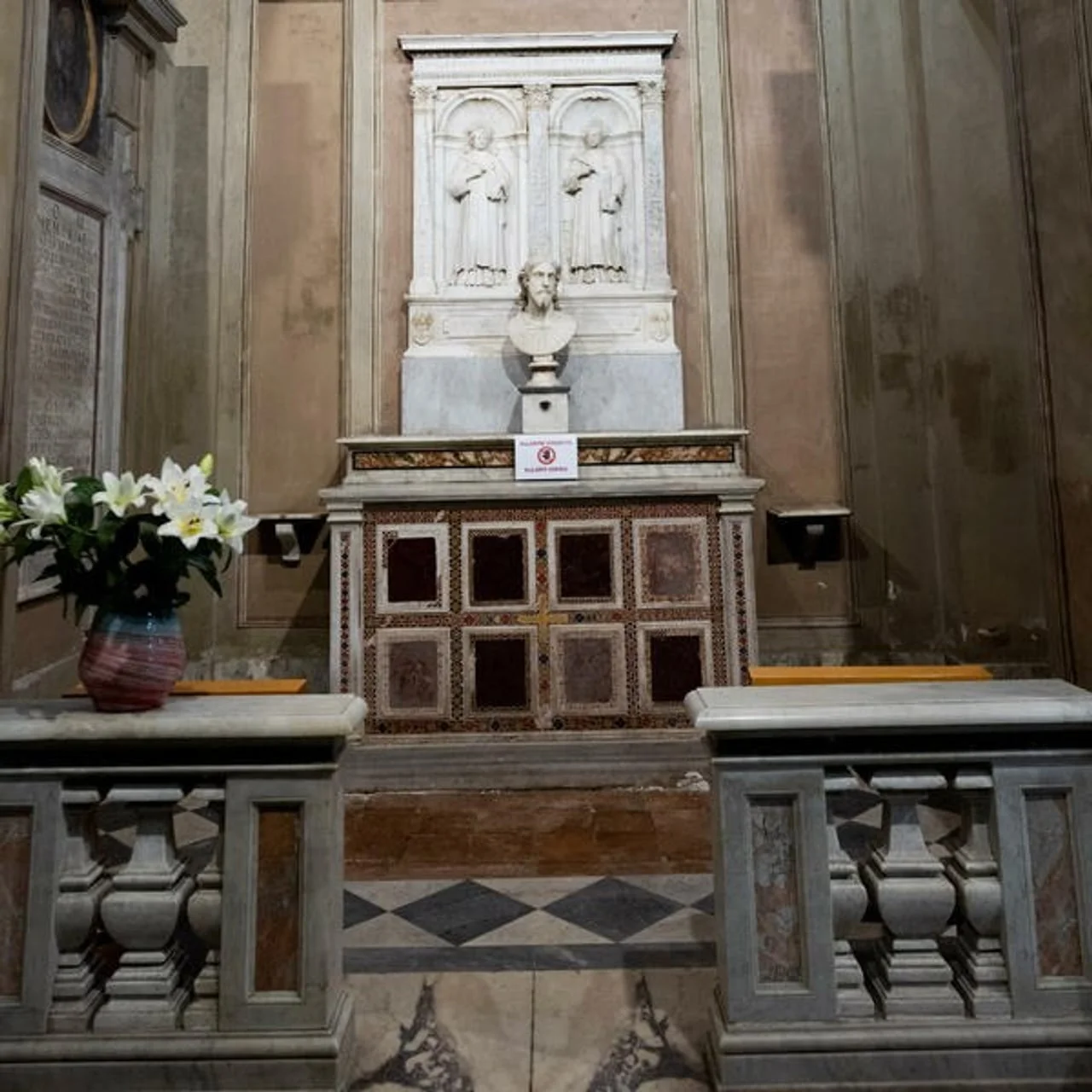 Mali oltar s bistom i bijelim cvijećem u vazi sa strane.