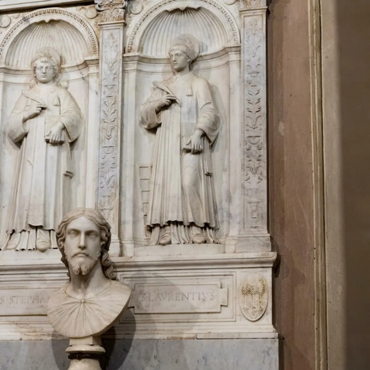 Detalj reljefa sa svecima iznad mramorne biste Krista.