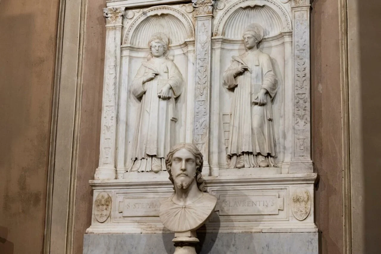 Krupni plan mramornih figura i biste u niši crkve.