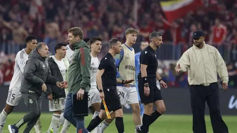 Igrači Real Madrida okružuju suca Slavka Vinčića na nogometnom terenu.