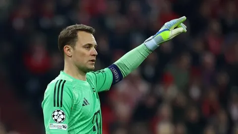 Manuel Neuer u zelenom vratarskom dresu pokazuje rukom prema suigračima na terenu.