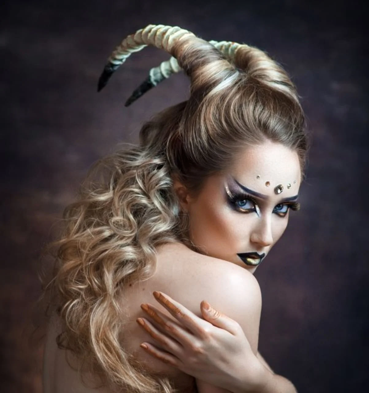 Žena s dugim rogovima i izraženom šminkom gleda preko ramena