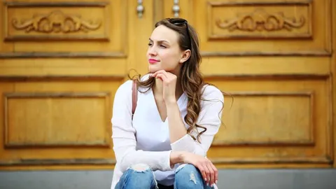 Zamišljena žena sjedi ispred ukrašenih drvenih vrata