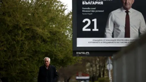 Stariji muškarac prolazi pored velikog predizbornog plakata Rumena Radeva u Bugarskoj.