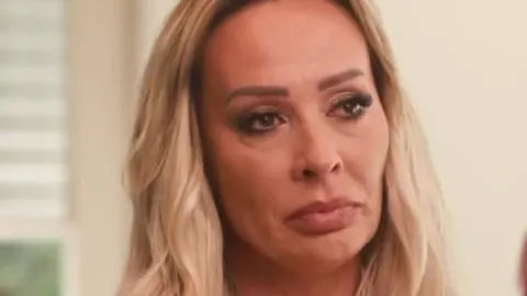 Krupni kadar lica plavokose žene ozbiljnog i sjetnog izraza lica.