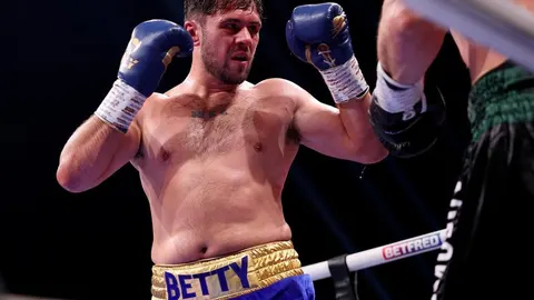 Dave Allen u boksačkom ringu s plavim rukavicama u obrambenom stavu.