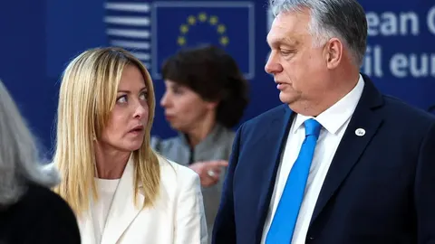 Giorgia Meloni i Viktor Orban u razgovoru ispred zastave Europske unije.