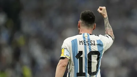 Lionel Messi s leđa u dresu Argentine s podignutom šakom na stadionu.