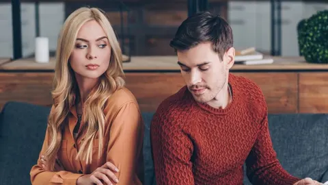 Ozbiljan muškarac i žena sjede leđima okrenuti jedno drugome u dnevnom boravku.