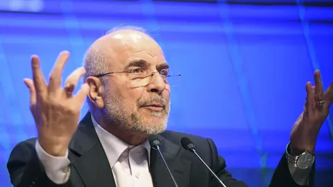 Mohammad Bagher Ghalibaf govoreći za govornicom s podignutim rukama.