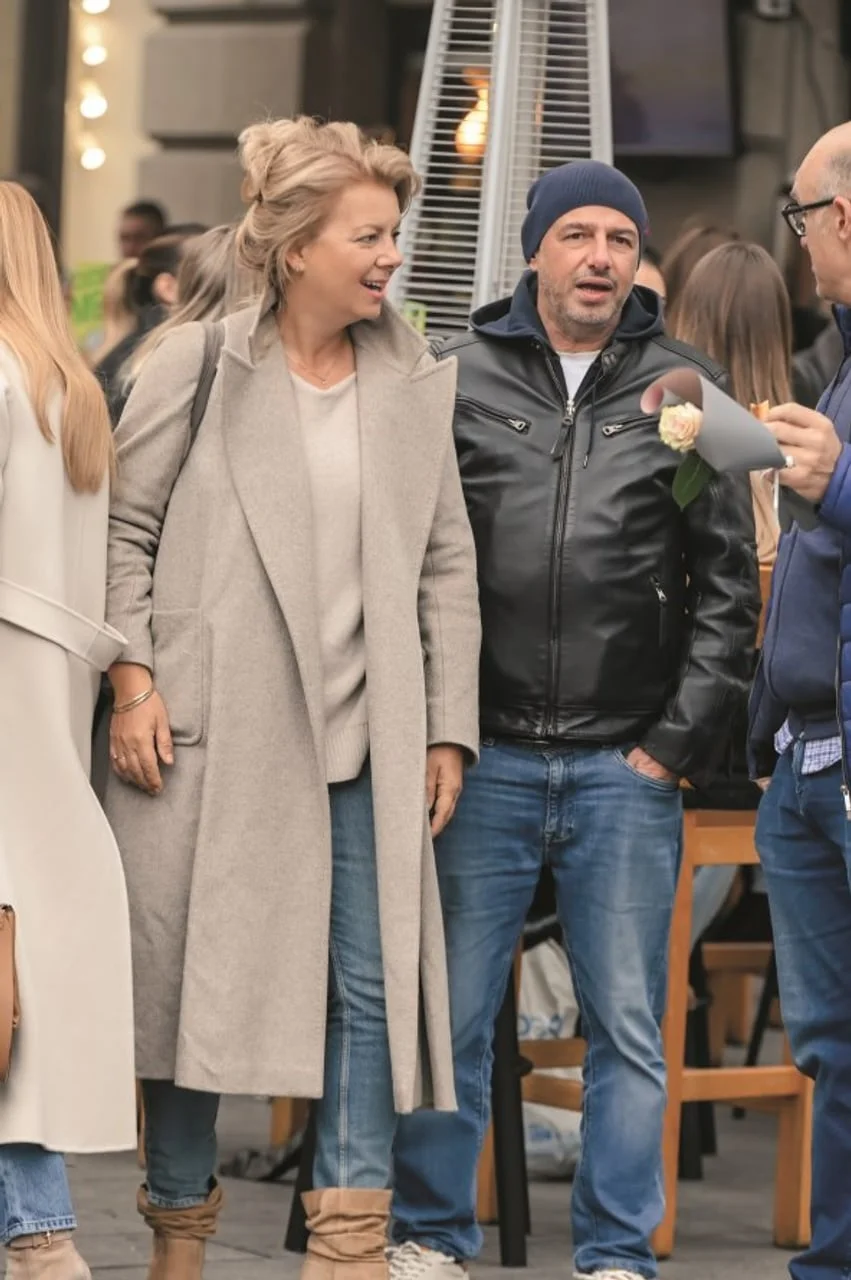 Mirjana Hrga u bež kaputu hoda gradom u društvu muškarca u kožnoj jakni.