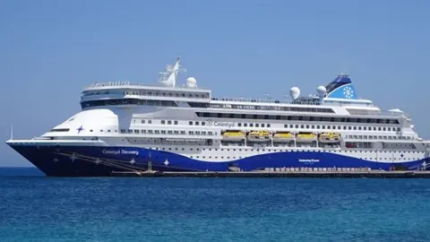 Veliki bijelo-plavi putnički brod Celestyal Discovery plovi mirnim morem.