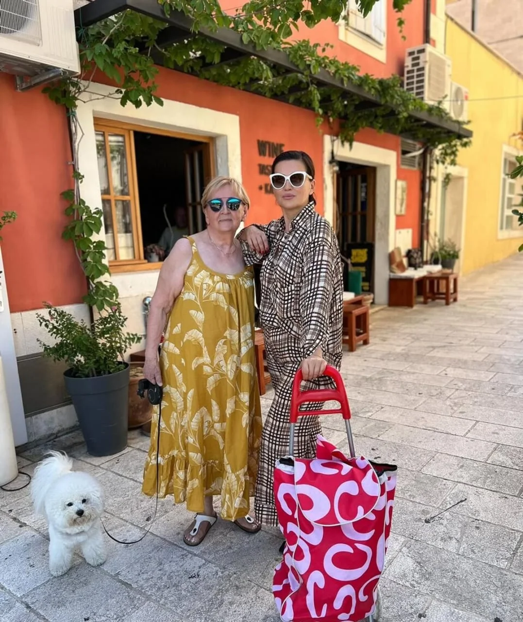 Nina Badrić i njezina majka Mila stoje na ulici s malim bijelim psom