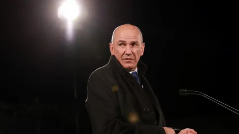 Janez Janša u tamnom kaputu na otvorenom pod reflektorima