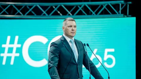 Filip Adžić stoji za govornicom ispred plavog ekrana tijekom službenog obraćanja.