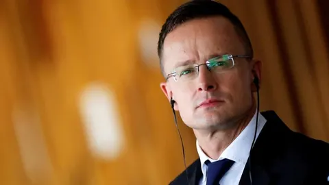 Péter Szijjártó s naočalama i slušalicama gleda ozbiljno u stranu.