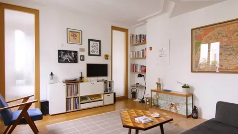 Svijetao dnevni boravak s bijelim zidovima, drvenim namještajem i bibliotekom