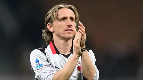 Luka Modrić u dresu milanskog kluba plješće na nogometnom terenu.