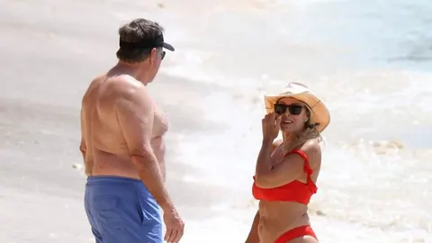 Bill Belichick i Jordon Hudson razgovaraju na pješčanoj plaži u kupaćim kostimima.