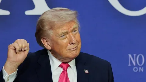 Donald Trump s podignutom šakom ispred plave pozadine