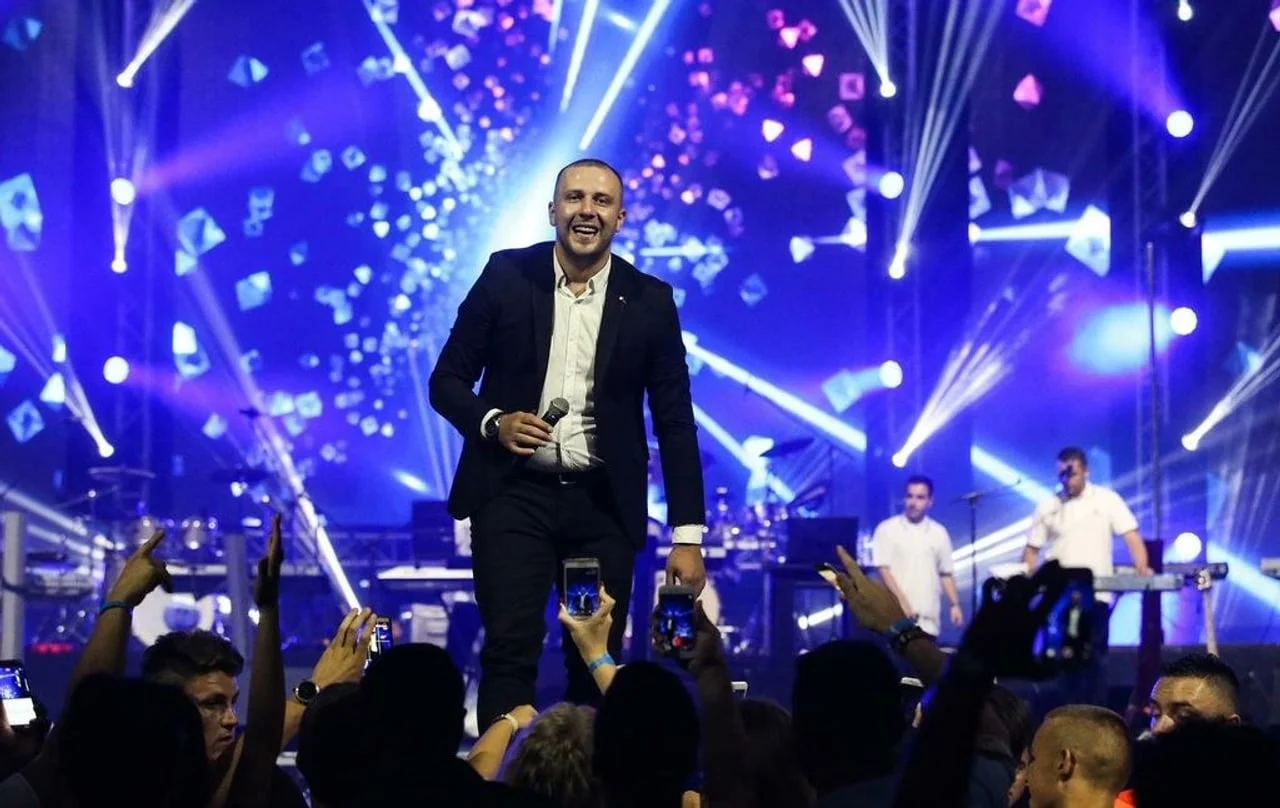Dado Polumenta pjeva na pozornici pred publikom uz plave svjetlosne efekte