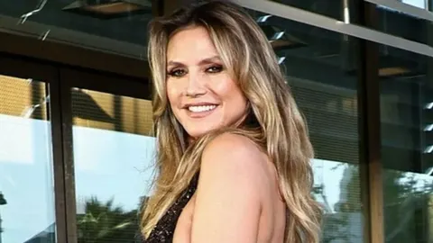 Heidi Klum u crnoj haljini sa šljokicama pozira na crvenom tepihu.