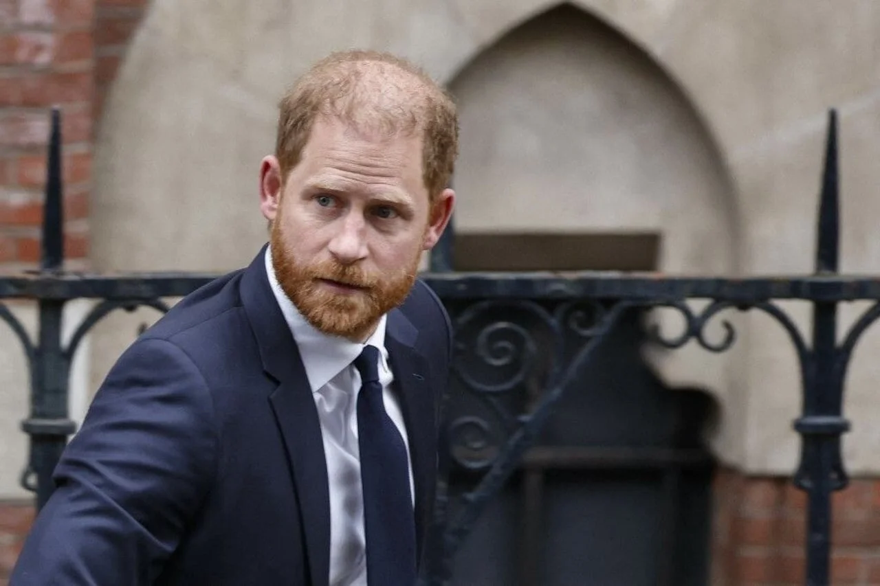 Princ Harry u tamnom odijelu ispred zgrade od opeke