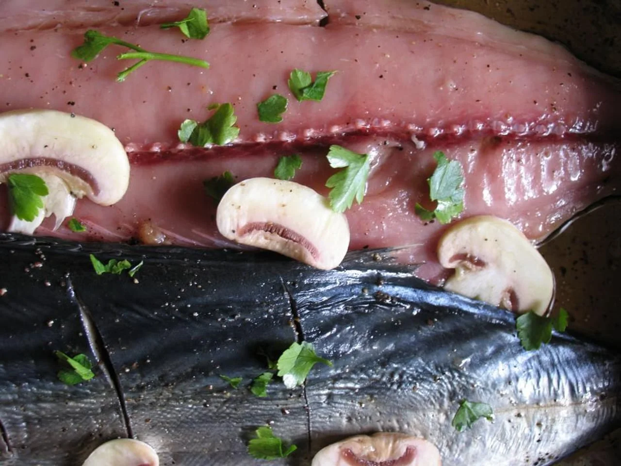 Sirovi fileti plave ribe začinjeni peršinom i gljivama