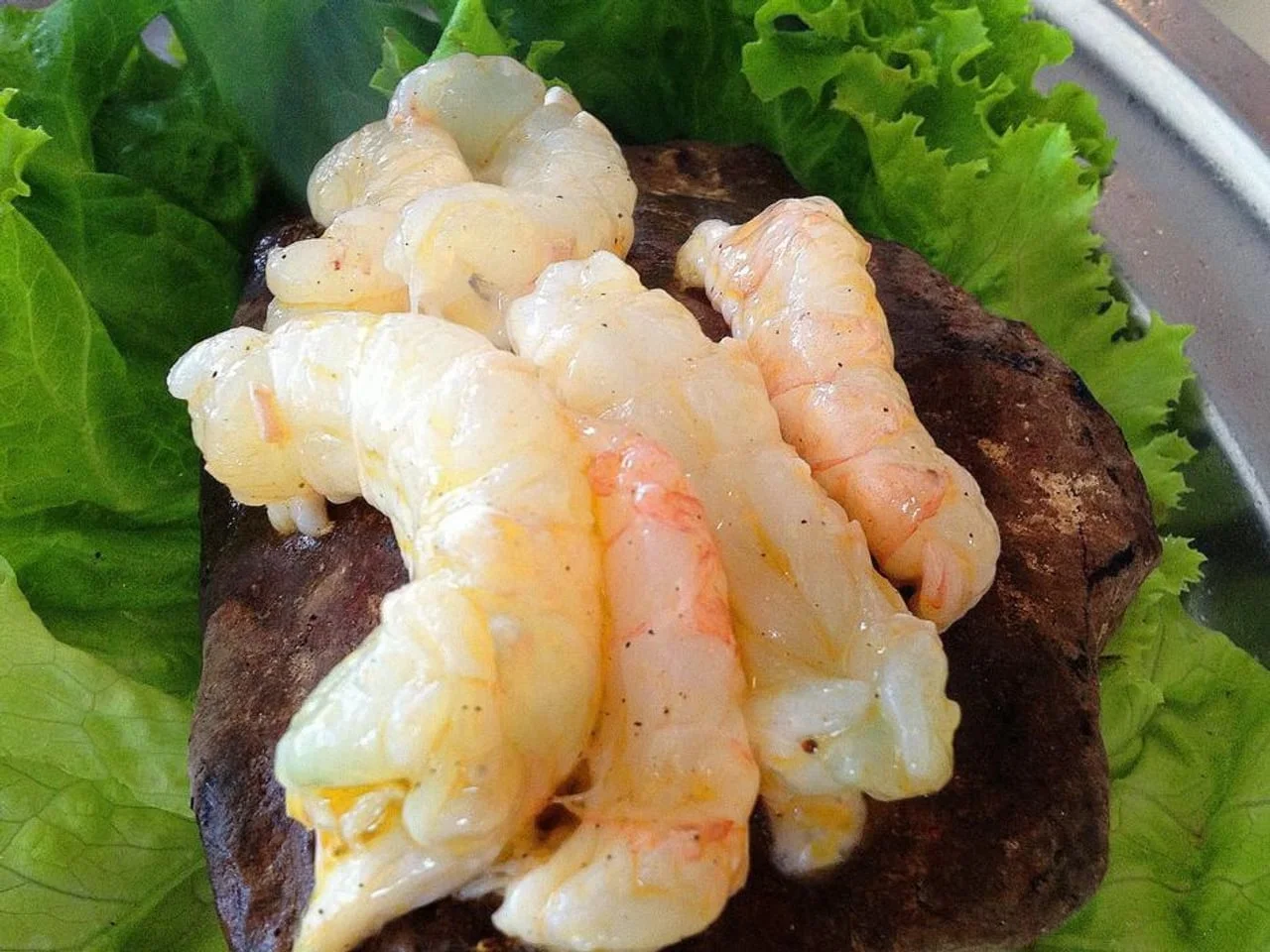 Očišćeni sirovi repovi škampa na podlozi od zelene salate