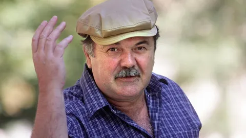 Portret glumca Filipa Radoša s kapom i brkovima u kariranoj košulji.