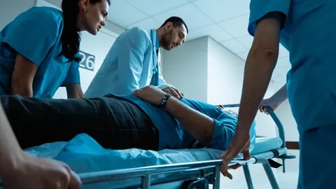 Medicinsko osoblje vozi pacijenta na kolicima u bolničkom hodniku.