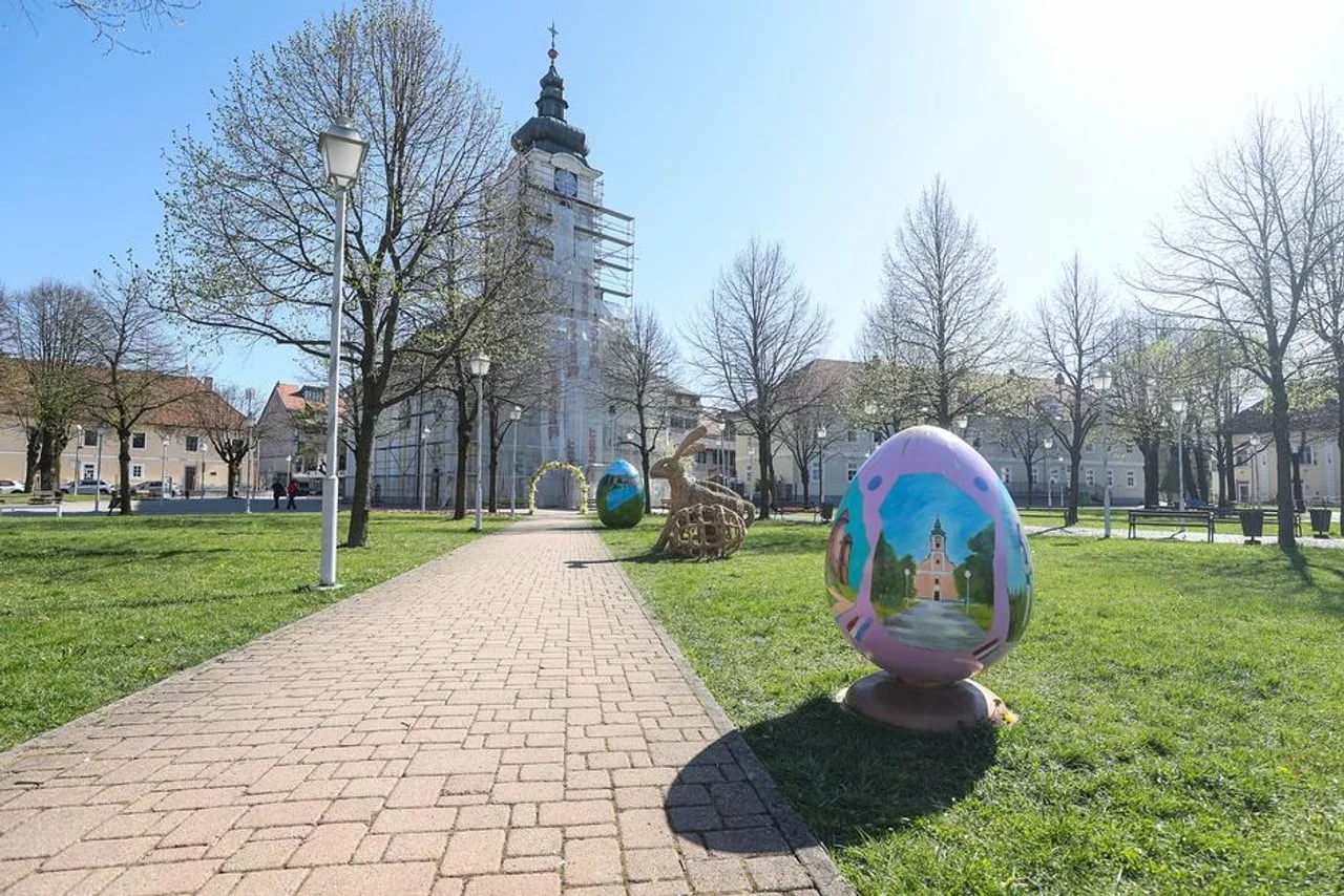 Popločana staza u parku s velikim uskršnjim jajima ispred crkve u Ogulinu.
