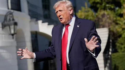 Donald Trump u odijelu i crvenoj kravati govori ispred Bijele kuće