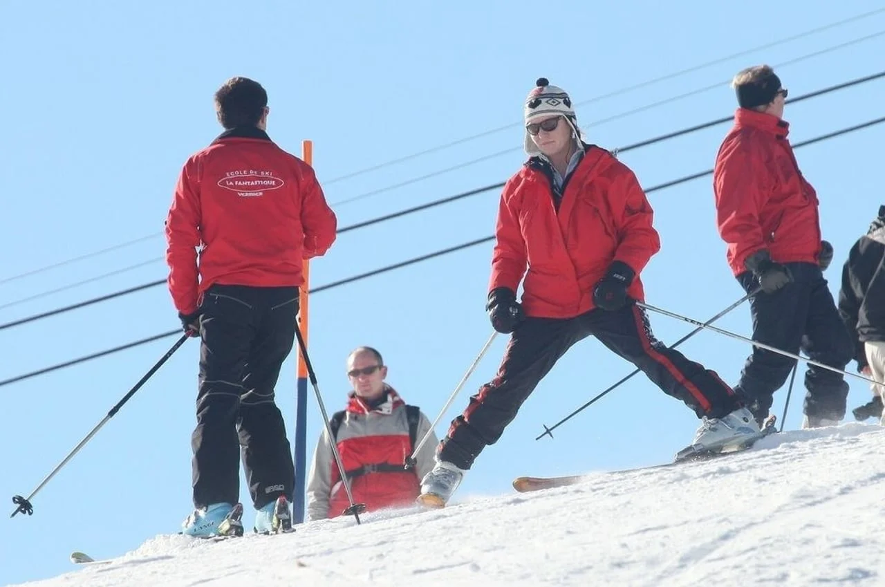Skupina skijaša u crvenim jaknama na snježnoj padini