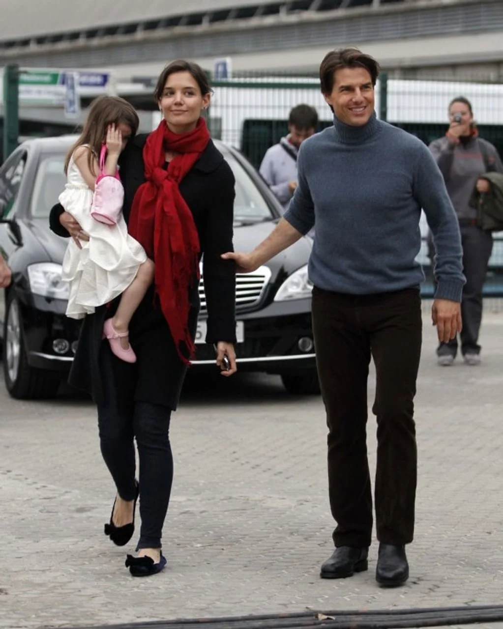 Katie Holmes drži Suri u naručju dok Tom Cruise hoda uz njih