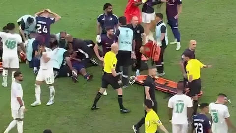 Medicinsko osoblje i igrači oko ozlijeđenog nogometaša na travnjaku.