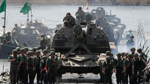 Vojna kolona s tenkovima i vojnicima prelazi pontonski most preko rijeke.