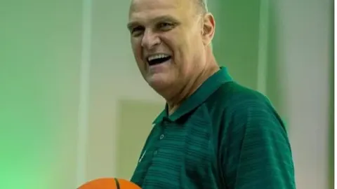 Nasmiješeni Oscar Schmidt u zelenoj majici drži košarkašku loptu