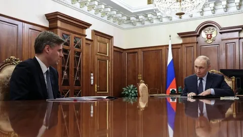 Vladimir Putin sjedi za velikim drvenim stolom tijekom službenog sastanka u Kremlju.