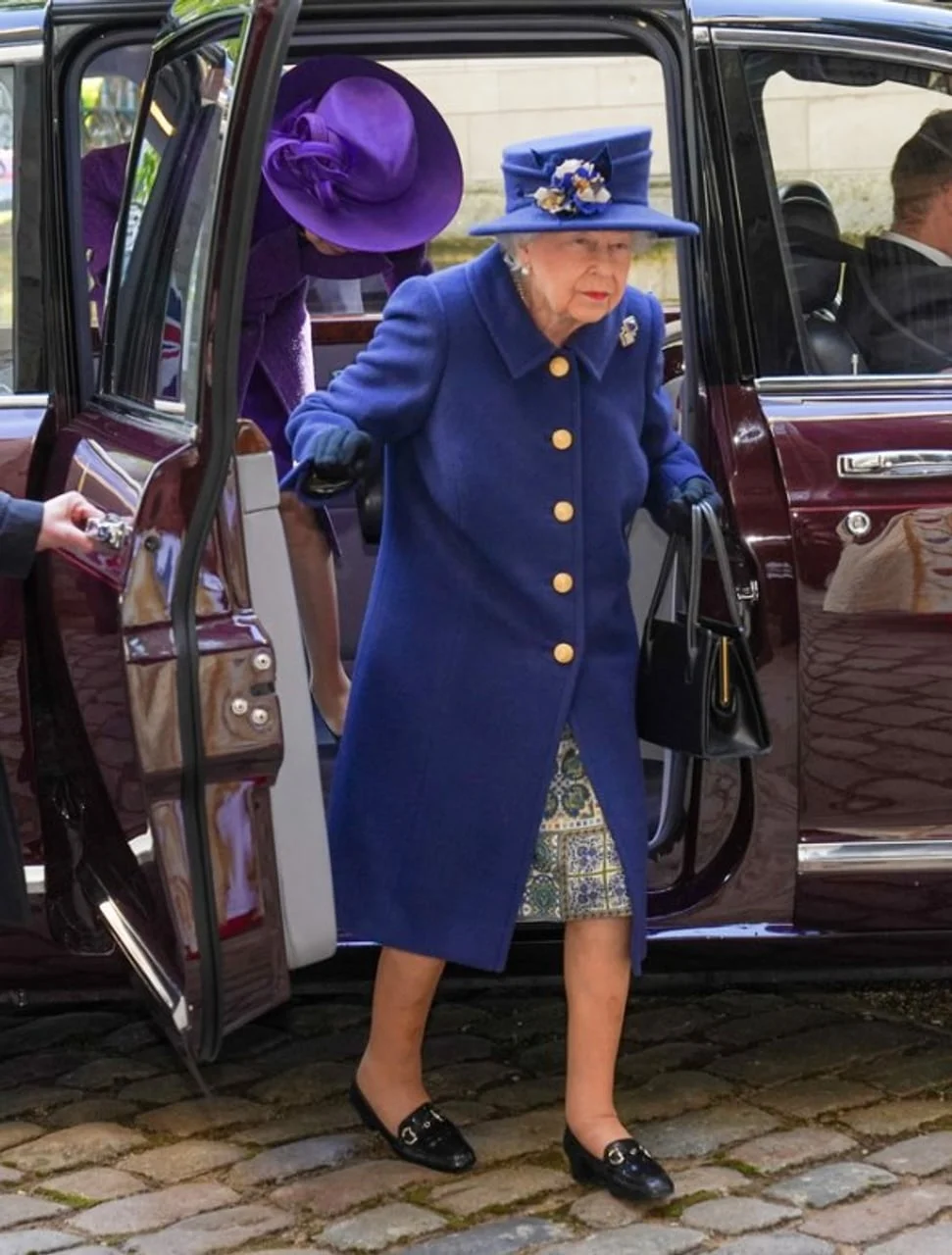 Kraljica Elizabeta II. izlazi iz automobila u plavom kaputu