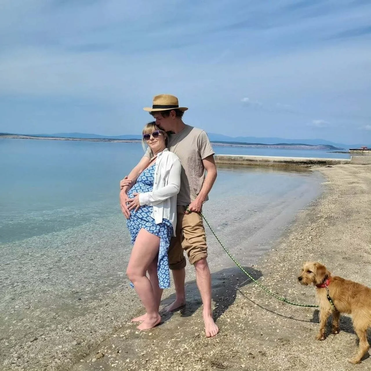 Trudna Jagoda Kumrić i Konstantin Haag sa psom na pješčanoj plaži.