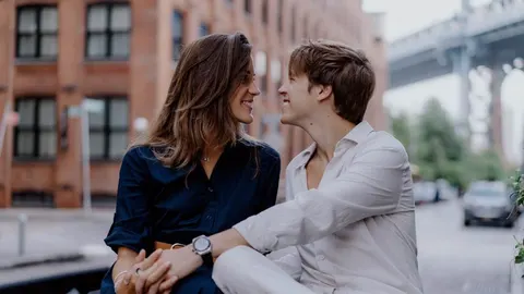 Mladi par se nasmijano gleda u oči na gradskoj ulici.