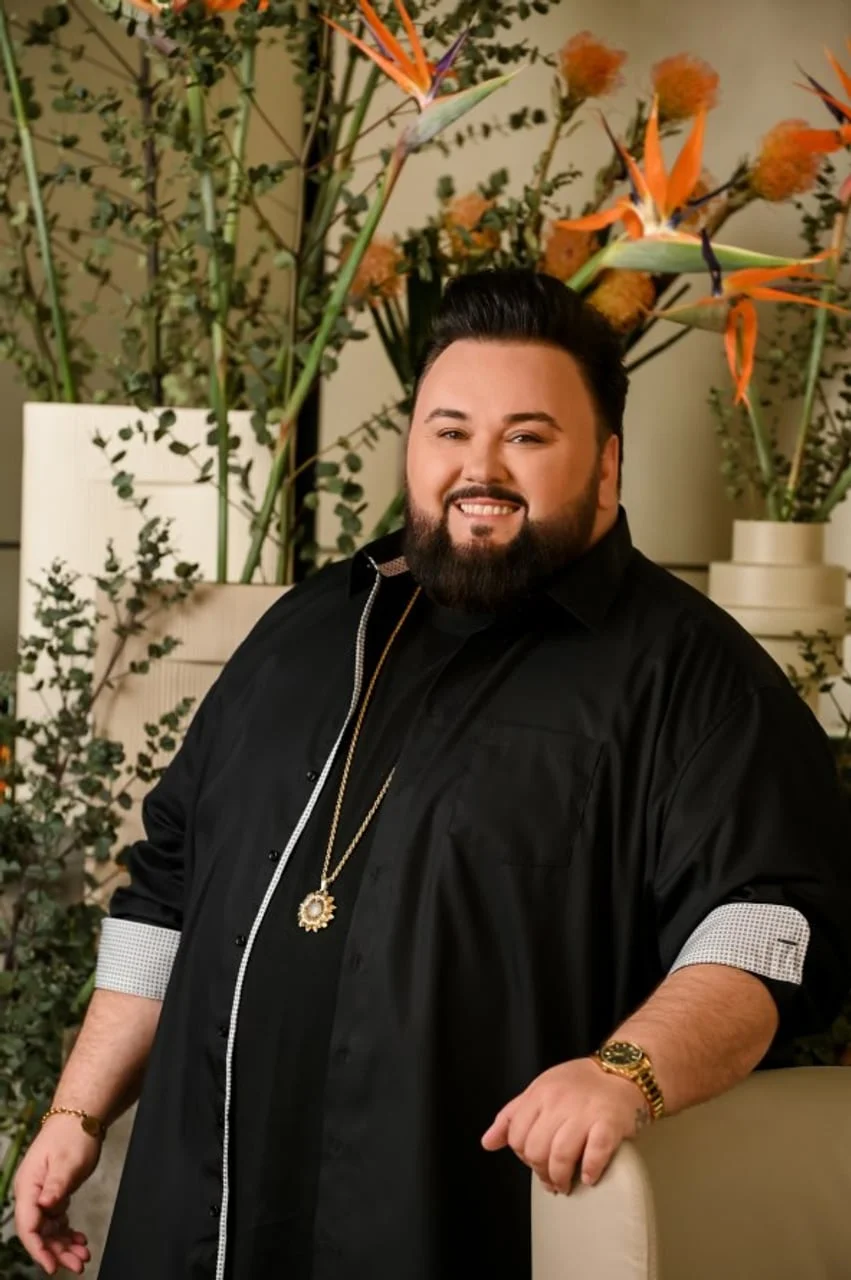 Jacques Houdek u crnoj košulji pozira ispred cvjetnog aranžmana